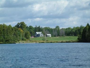 Blick vom See zum Ferienhaus mit Strand im Vordergrund