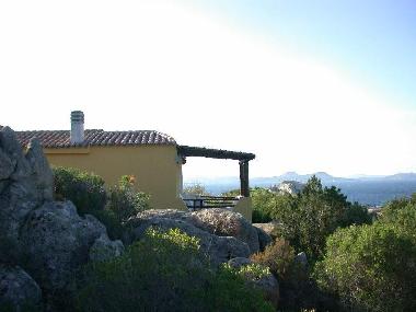 Seitenansicht auf die Villa Daniela mit berdachter Terrasse und dahinter Blick aufs Meer