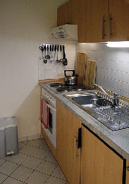 Küche mit Röhre, Kochplatten, Kühlschrank, Spüle und Geschirr