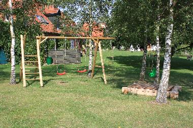 Spielplatz mit Schaukeln und Sandkasten im Garten
