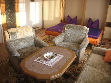 Sitzgarnitur im Wohnzimmer mit den ausgeklappten Schrankbetten im Hintergrund