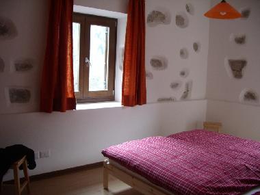 Schlafraum mit auf Sicht herausgearbeiteten Natursteinen