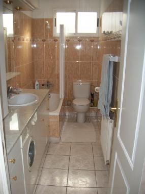 Bsdezimmer mit Badewanne, Duschtrennwand und WC.