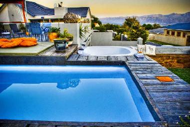 Blick auf Pool und Jacuzzi mit Meer- und Bergblick.