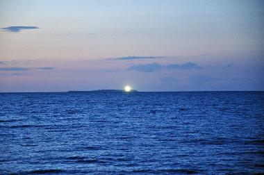 Blick vom Strand auf die Insel Oie mit Leuchtturm.