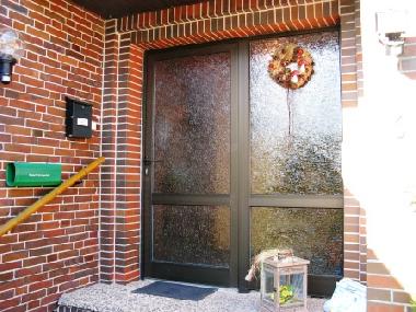 Eingangsbereich zur Ferienwohnung Kutscherhuus. Vor dem Haus befindet sich ein grosser Parkplatz.