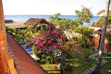 Balkon mit Blick auf den tropischen ummauerten Garten und das Meer.