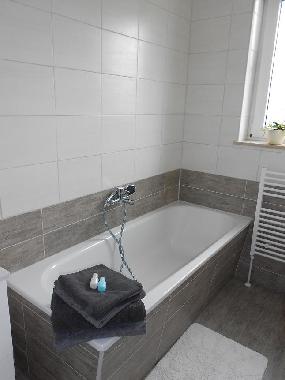 frisch renoviertes Badezimmer mit Badewanne und Waschbecken mit Schrank