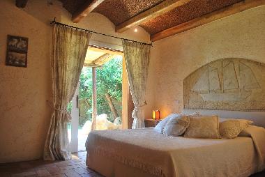 Schlafzimmer mit Doppelbett und Zugang zum Garten