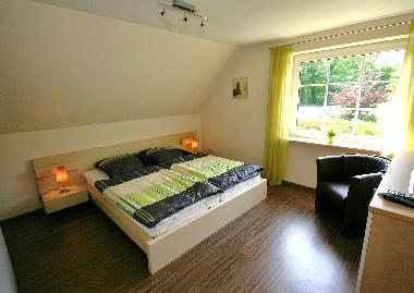 Schlafzimmer 1 im OG mit Doppelbett, Sitzecke und TV