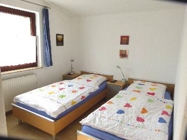 Schlafzimmer mit Einzelbetten und Fernseher
