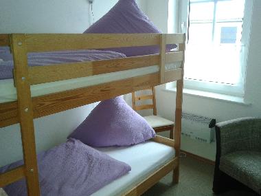Weiteres Schlafzimmer mit Doppelstockbett und historischem Kachelofen im EG.