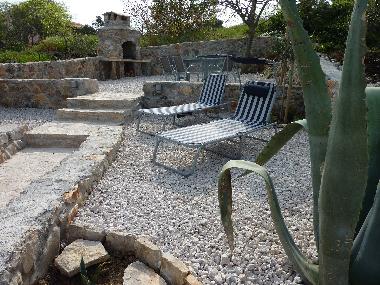 Der Blick auf Gartenliegen und Grill.