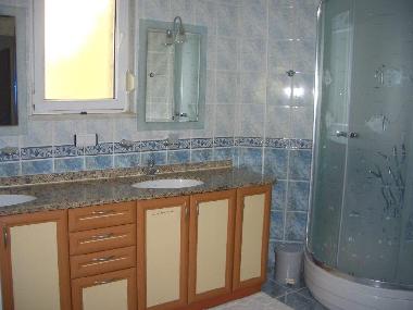 Grossz�giges Badezimmer mit Doppelwaschbecken, beleuchteten Spiegeln und Dusche.